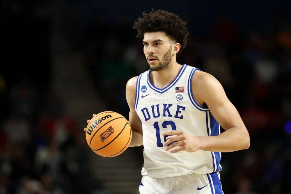 Cameron Boozer, wearing a white and blue Duke jersey, dribbles the ball down the court.